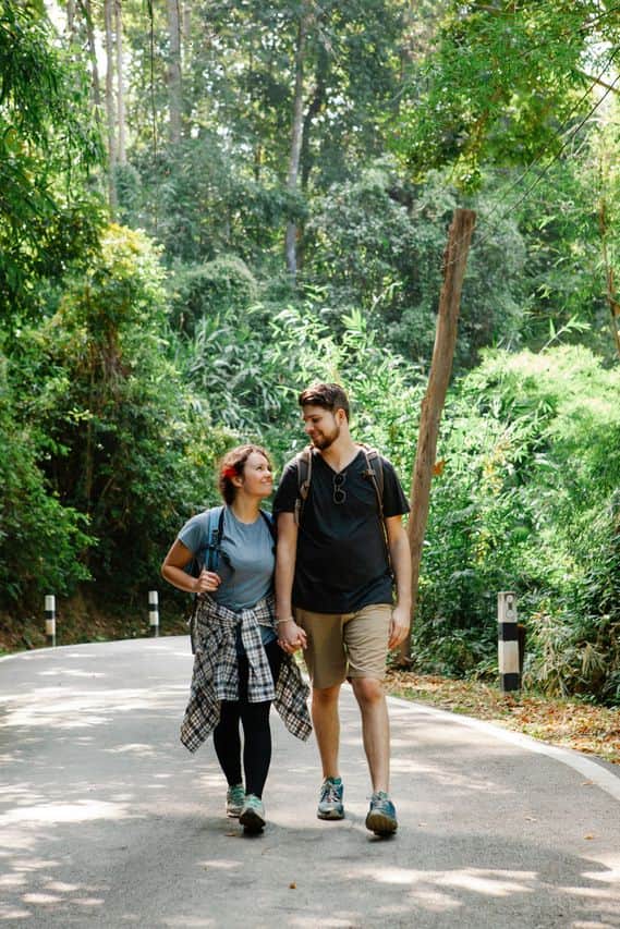 Couple walking on a tree-lined forest road